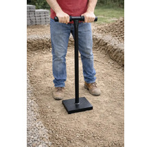 Man verdicht grond met een handstamper