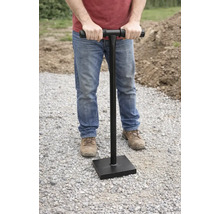 Een man gebruikt een handstamper om de grond te verdichten.