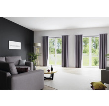 Woonkamer met bank, ramen met gordijnen en staande lamp