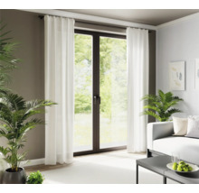 Woonkamer met witte gordijnen voor een terrasdeur en kamerplanten