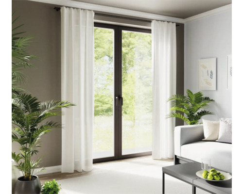 Woonkamer met witte gordijnen voor een terrasdeur en kamerplanten