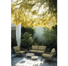 Tuinscene met lounge set en bijzettafels onder een bloeiende boom