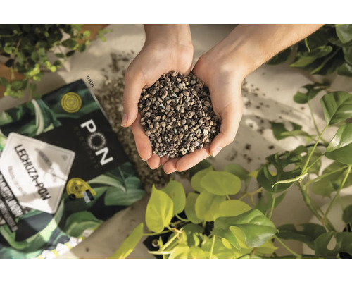 Een handvol Lechuza Pon plantensubstraat boven een verpakking en planten