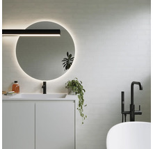 Moderne badkamer met ronde spiegel, wastafel, kraan en bad.