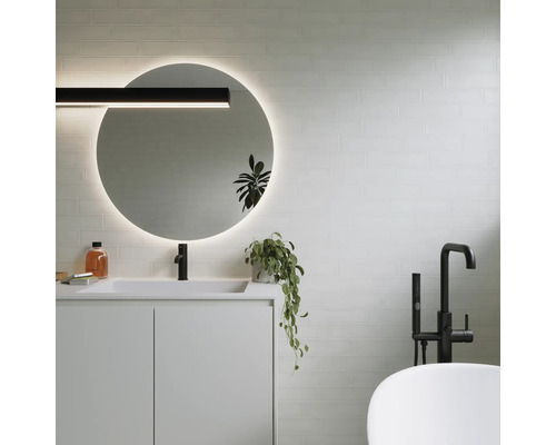 Moderne badkamer met ronde spiegel, wastafel, kraan en bad.