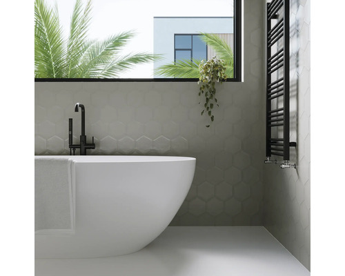 Badkamer met bad, handdoekradiator en zeshoekige wandtegels