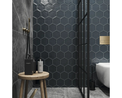 Badkamer met zeshoekige wandtegels, douche, toilet en houten kruk