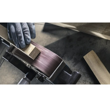 Close-up van een bandschuurmachine die een werkstuk bewerkt