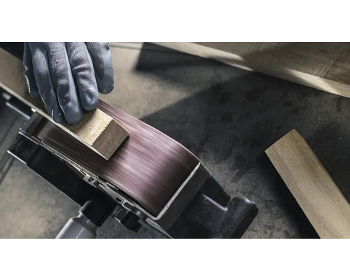 Close-up van een bandschuurmachine die een werkstuk bewerkt