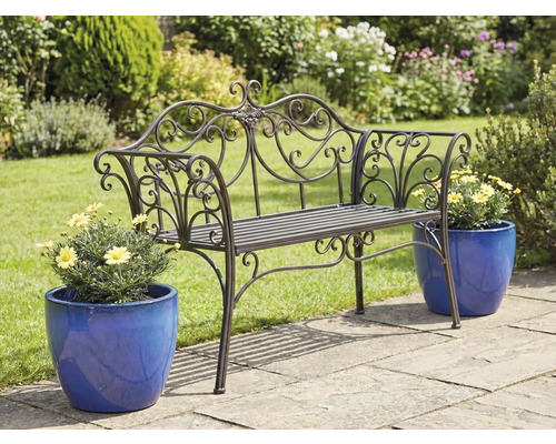 Versierde metalen tuinbank met bloempotten op een tuinterras