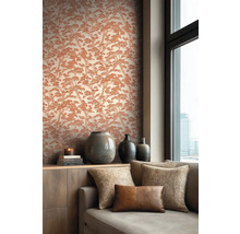 Vliesbehang met boompatroon in een woonkamer met bank, kussens, houten dressoir en keramische vazen bij een raam.