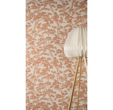 Behang met dennenboompatroon op de achtergrond, met een moderne vloerlamp met geplooide kap en houten poten op de voorgrond.