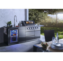 Moderne buitenkeuken met barbecue, gootsteen, koelkast en werkbladen op een terras met uitzicht op de tuin