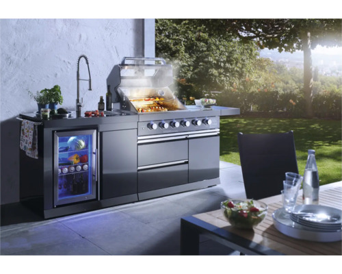 Complete buitenkeuken met barbecue, gootsteen, werkblad en drankkoelkast in de tuin.