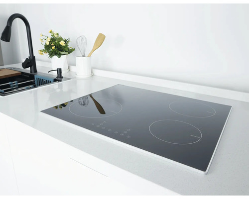 Inductiekookplaat met vier kookzones in een lichte, moderne keuken op een wit aanrechtblad naast de gootsteen en kraan.