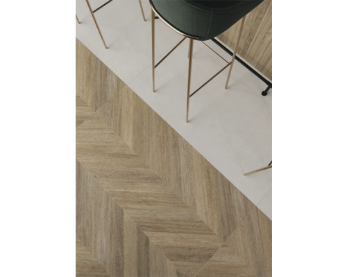 Keramische vloertegels in houtlook met chevronpatroon naast lichte tegels, moderne barkruk.