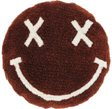 Rond bruin sierkussen van pluizige stof met een wit smiley-gezicht bestaande uit kruisjes als ogen en een glimlachende mond.