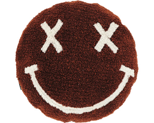 Rond bruin sierkussen van pluizige stof met een wit smiley-gezicht bestaande uit kruisjes als ogen en een glimlachende mond.