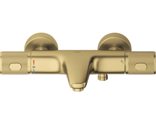 Grohe thermostatische badkraan in goud met gekartelde handgrepen, baduitloop en temperatuurbeveiliging op 38 graden Celsius.