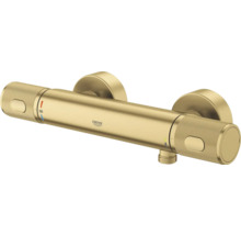 Grohe douchethermostaat in goud met gekartelde grepen, cilindrisch design en temperatuurinstelling op 38 graden.