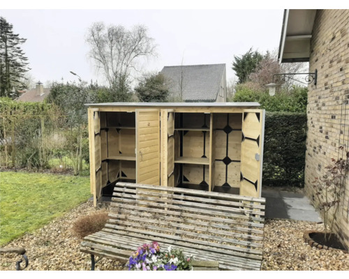 Open houten tuinkast met vier compartimenten en legplanken, geplaatst in een tuin naast een houten bank op grind.