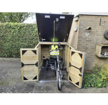 Houten fietsenberging met geopende deuren en klep, waarin een driewieler staat.