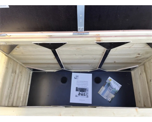 Binnenaanzicht van een houten opbergbox voor de tuin met zwarte bodem, ventilatiegaten en handleidingen.