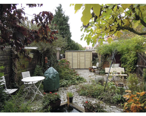 Tuin met een licht houten tuinhuisje, bestrating, witte tuintafel en stoelen, weelderige beplanting en een vijver.