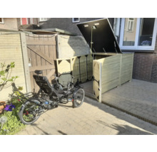 Grote houten fietsenberging met open deksel en deuren, met een ligfiets op een betegeld terras in een lichte tuin.