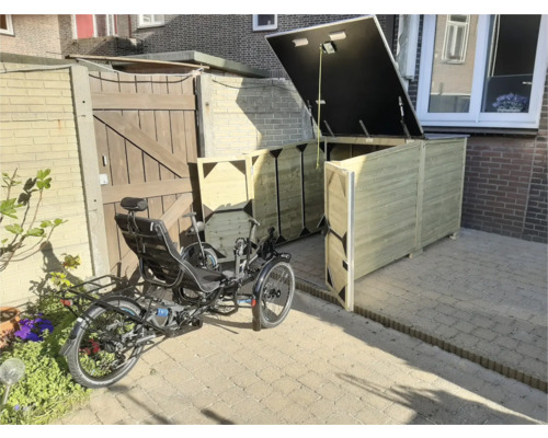 Grote houten fietsenberging met open deksel en deuren, met een ligfiets op een betegeld terras in een lichte tuin.