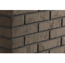 Steenstrips met baksteenlook met ruwe gestructureerde oppervlakte en donkere voegen op een muurhoek.