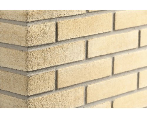 Steenstrips met ruwe textuur in halfsteensverband met grijze voegen.