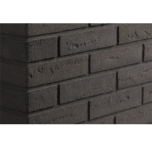 Gestructureerde donkergrijze steenstrips in metselwerklook op een muurhoek met een ruw oppervlak.