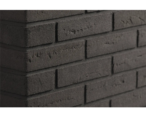 Gestructureerde donkergrijze steenstrips in metselwerklook op een muurhoek met een ruw oppervlak.