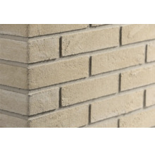 Detailopname van een hoek van een muur met lichte, gestructureerde gevelstenen.