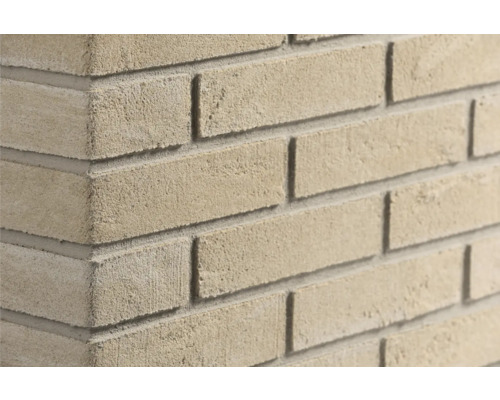 Detailopname van een hoek van een muur met lichte, gestructureerde gevelstenen.