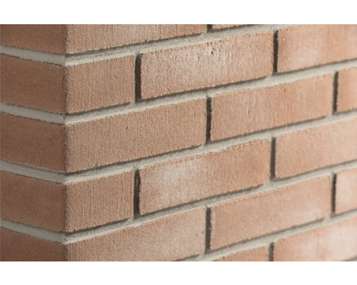 Roodbruine steenstrips met baksteenlook voor de wandafwerking met een ruw oppervlak en grijze voegen.