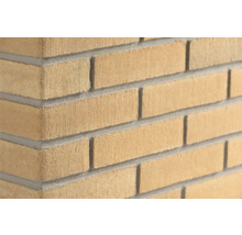 Gele steenstrips met baksteenlook en gezandstraald oppervlak, hoekaanzicht van een metselwerk muur.