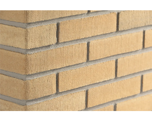 Gele steenstrips met baksteenlook en gezandstraald oppervlak, hoekaanzicht van een metselwerk muur.