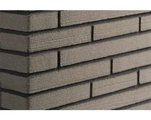 Close-up van een muur met smalle, gestructureerde steenstrips en diepe horizontale voegen.