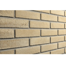 Steenstrips met een ruw, zandkleurig oppervlak en grijze voegen.