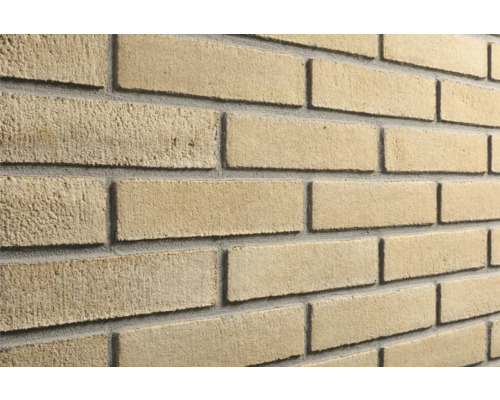 Steenstrips met een ruw, zandkleurig oppervlak en grijze voegen.