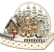 Houten kersttafereel met verlichte vakwerkhuizen, sneeuwpoppen op een bankje en dennenbomen.