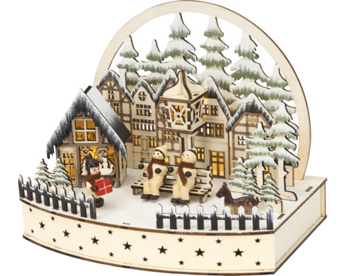 Houten kersttafereel met verlichte vakwerkhuizen, sneeuwpoppen op een bankje en dennenbomen.