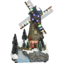 Kerstdecoratie met verlichte windmolen, kerstmanfiguur, besneeuwde dennenbomen en een beekje op een rotsachtige basis.