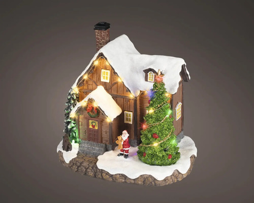 Miniatuur kersthuisje van hout met besneeuwd dak, verlichte kerstboom en klein kerstmanfiguurtje.