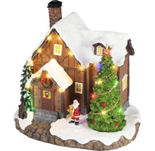 Kerstdorp miniatuur met een besneeuwd huis, een verlichte kerstboom, een kerstmanfiguur en een lichtsnoer.