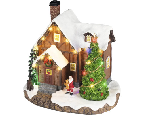 Kerstdorp miniatuur met een besneeuwd huis, een verlichte kerstboom, een kerstmanfiguur en een lichtsnoer.