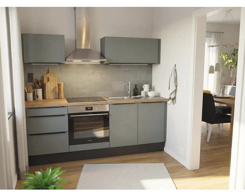 Moderne kitchenette met grijze kasten, houten aanrechtblad, inbouwoven, kookplaat, roestvrijstalen afzuigkap en grijze tegelwand.