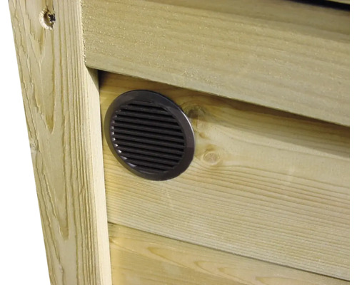 Rond ventilatierooster ingebouwd in een wand van houten planken.